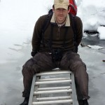 Man on ladder on frozen creek